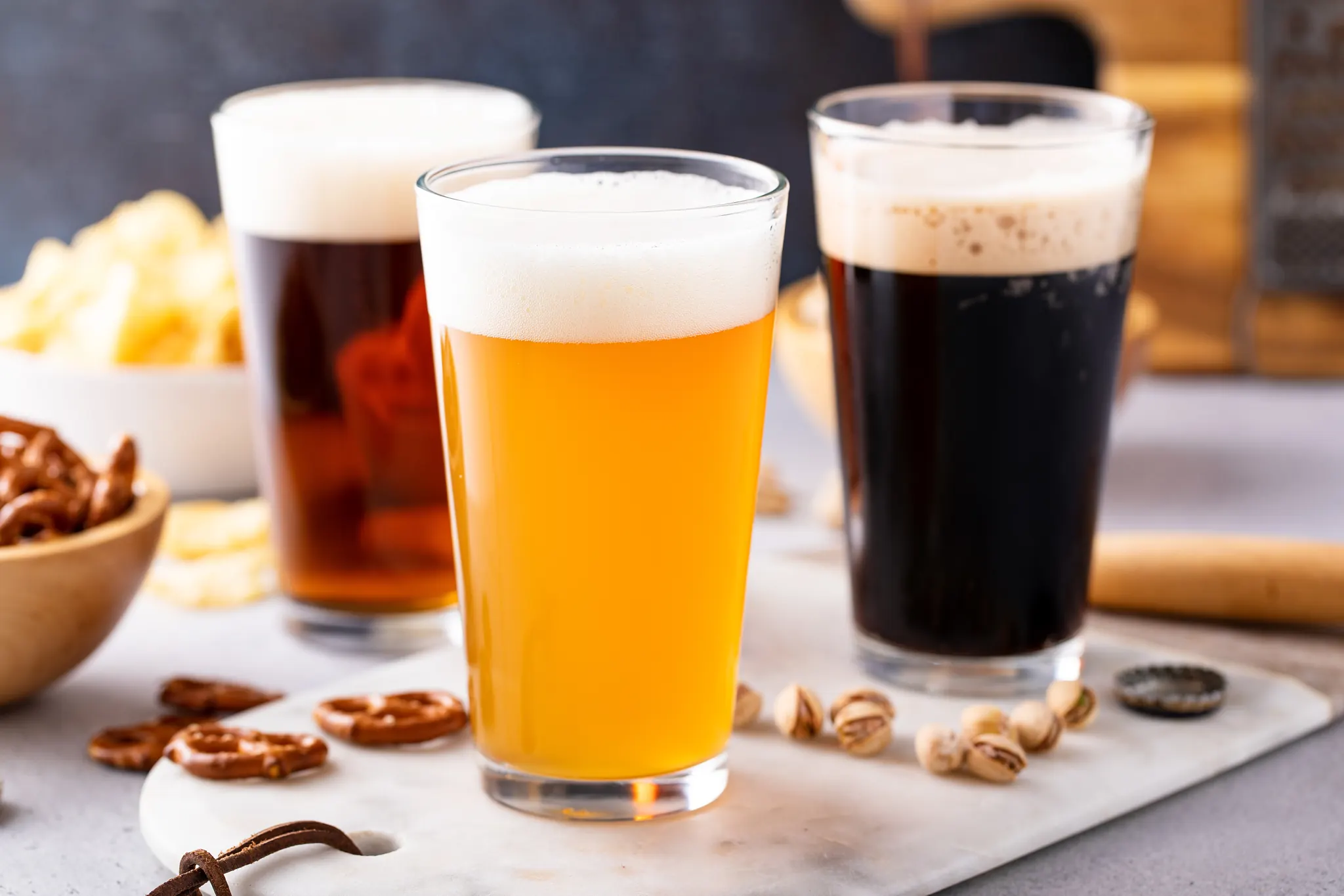 Three beers and snacks on a marble board